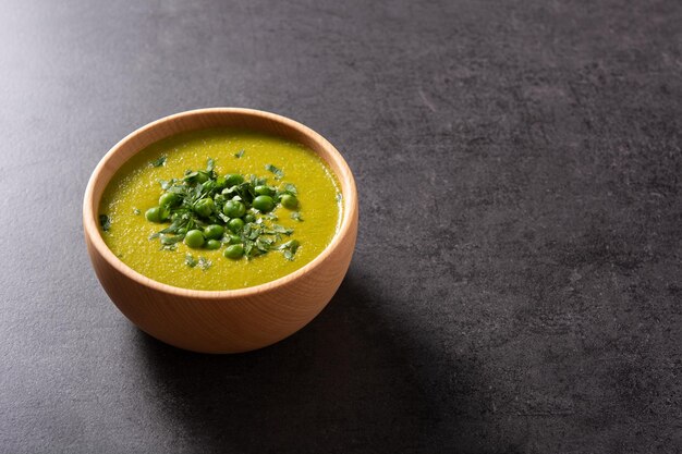 Grüne Erbsensuppe in einer Schüssel auf schwarzem Schieferhintergrund