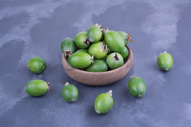 Grüne Feijoas in einer Holzschale auf blauer Oberfläche