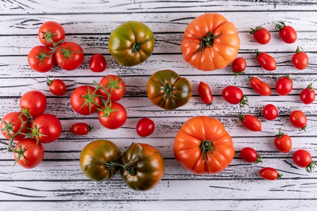 grüne orange Tomaten und Niederlassungen von Kirschtomaten auf weißem hölzernem