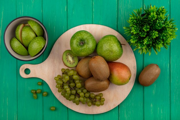 Grüne Äpfel der Draufsicht mit grünen Kiwi-Trauben und Birne auf einem Stand auf grünem Hintergrund