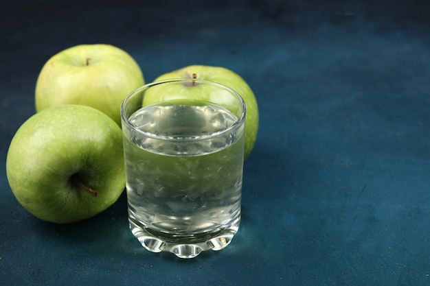 Grüne Äpfel mit einem Glas Apfelsaft.