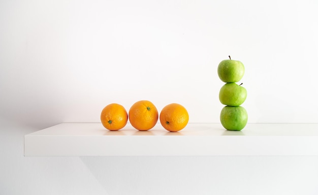 Grüne Äpfel und Orangen auf einer weißen Hintergrundnahaufnahme