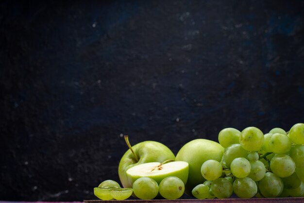 Grüne Trauben der Vorderansicht mit grünen Äpfeln auf Dunkelheit