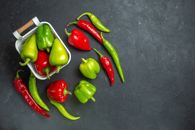 Grüne und rote Paprika von oben in Plastikkorb-Peperoni auf dunklem, freiem Platz