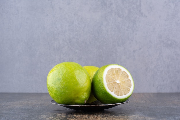 Grüne Zitronen isoliert in einer schwarzen Mini-Untertasse