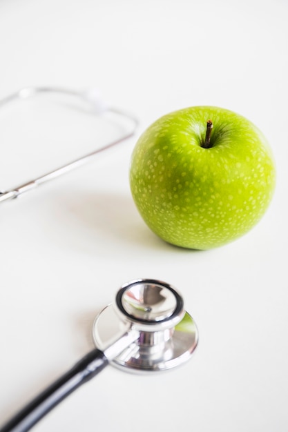 Grüner Apfel und Stethoskop auf weißem Hintergrund