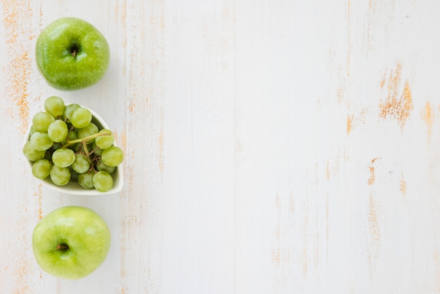 Grüner Apfel und Trauben auf weißem hölzernem Hintergrund