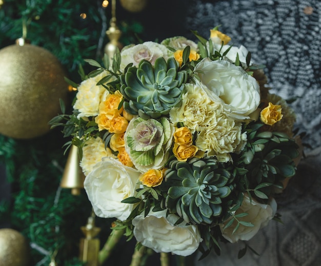 Grüner gelber Blumenstrauß mit goldener Weihnachtskugel.