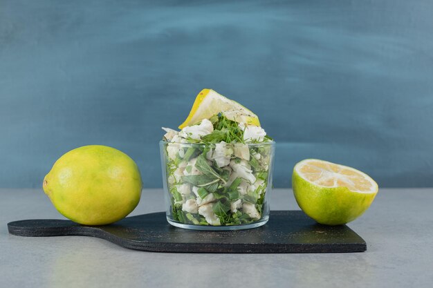 Grüner Kräutersalat in einer Tasse auf Betontisch.