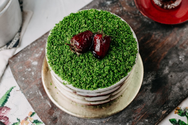 grüner Kuchen pulverisierter Obstkuchen mit geschnittenen Früchten rund lecker lecker auf grauem Schreibtisch