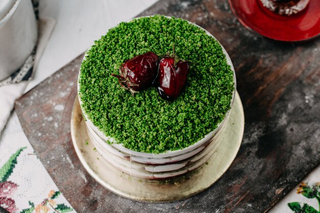 grüner Kuchen pulverisierter Obstkuchen mit geschnittenen Früchten rund lecker lecker auf grauem Schreibtisch