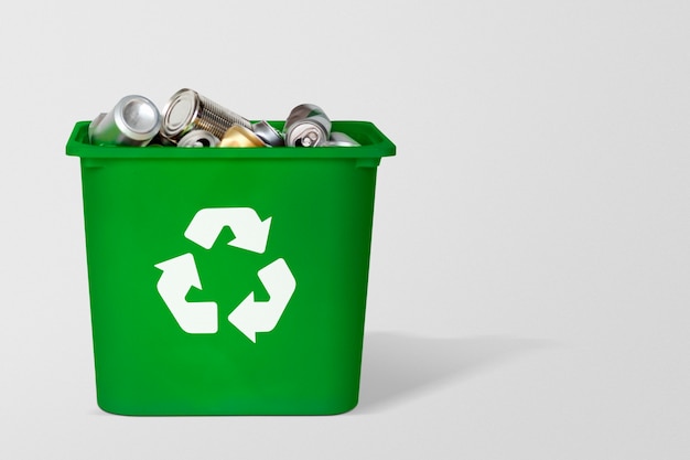 Kostenloses Foto grüner recycling-mülleimer gefüllt mit gebrauchten dosen mit designraum auf grauem hintergrund