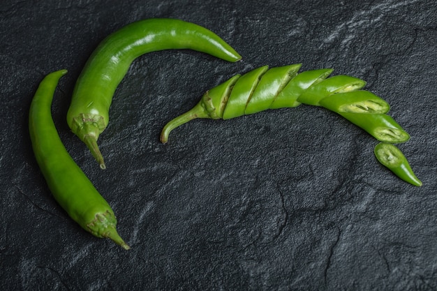 Grüner scharfer Chili-Pfeffer geschnitten oder ganz auf schwarzem Hintergrund. Hochwertiges Foto