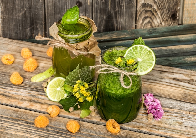 grüner Smoothie in einem Glas mit Limette, Kiwi und Beeren
