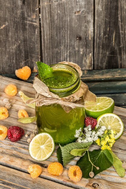 grüner Smoothie in einem Glas mit Limette, Kiwi und Beeren