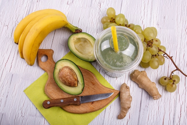 Grüner Smoothie mit Bananen, Ingwer, Traube und Avocado liegen auf dem