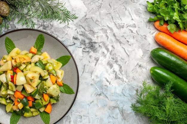 Grüner Tomatensalat der Draufsicht auf ovalem Tellergemüse auf dunklem Hintergrund