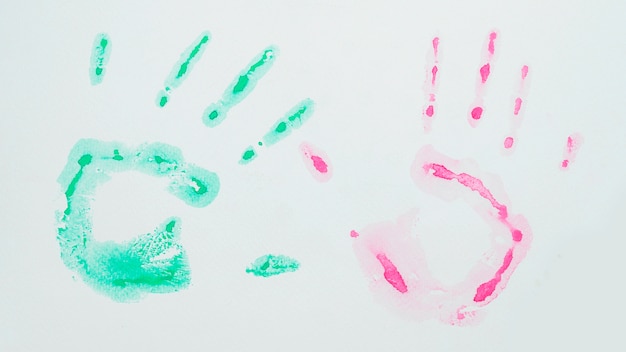 Grüner und rosafarbener Aquarellhandprint auf weißer Oberfläche