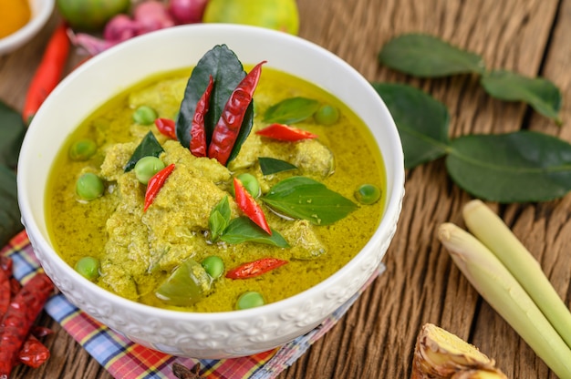 Kostenloses Foto grünes curry in einer schüssel mit limetten, roten zwiebeln, zitronengras, knoblauch und kaffirlimettenblättern