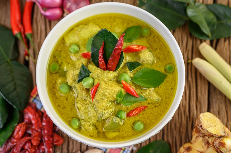 Kostenlose Foto grünes curry in einer schüssel mit limetten, roten zwiebeln, zitronengras, knoblauch und kaffirlimettenblättern