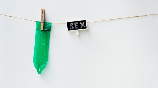 Grünes Kondom auf Wäscheleine mit weißem Hintergrund