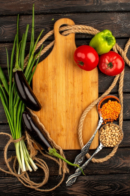 Grünes und gewürztes frisches Vitamin, reich an roten Tomaten, schwarzen Auberginen und grünem Paprika auf einem braunen rustikalen Holzboden