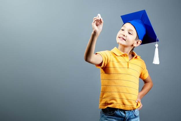 Grundschüler mit einer Abschlusskappe und einem Kreide