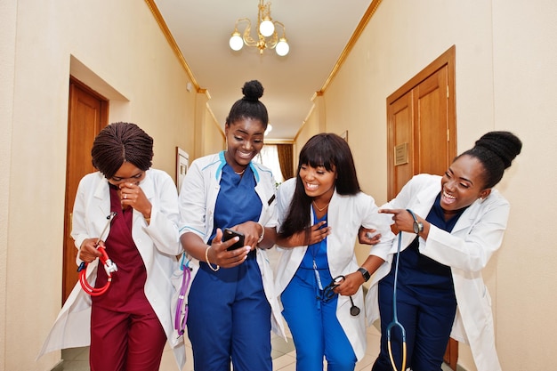 Kostenloses Foto gruppe afrikanischer medizinstudentinnen im college, die telefonieren und laut lachen