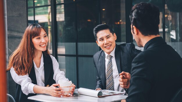 Gruppe asiatischer Geschäftsleute im Geschäftsviertel, die über neue Geschäfte und Wirtschaft im Freien sprechen