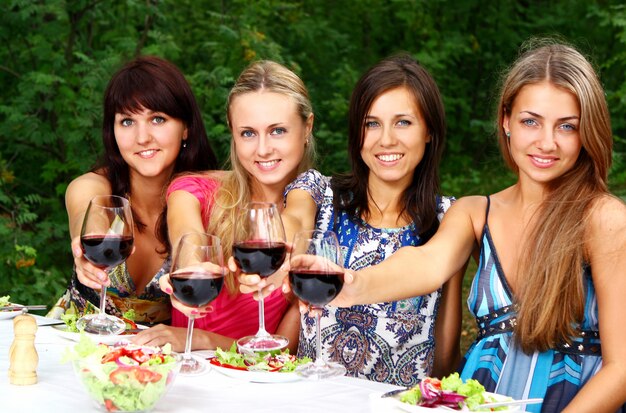 Gruppe der jungen Mädchen, die Wein im Park trinken