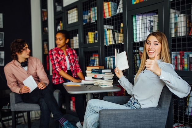 Gruppe ethnischer multikultureller studenten, die am tisch in der bibliothek sitzen