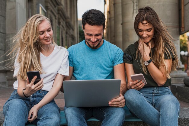 Gruppe Freunde, die an Telefonen und Laptop arbeiten