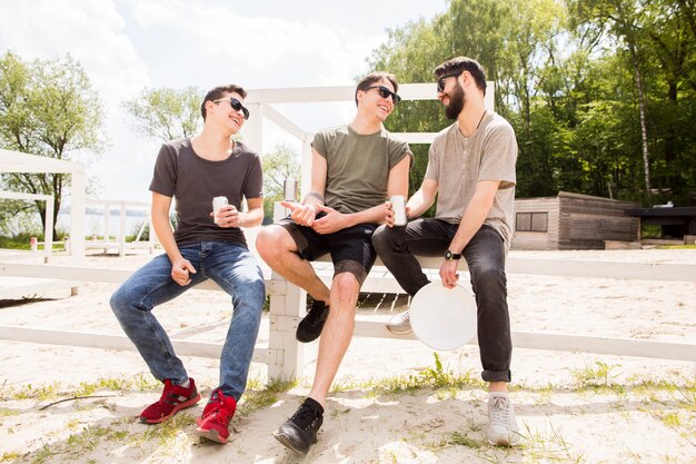 Gruppe Freunde, die auf Strandzaun plaudern