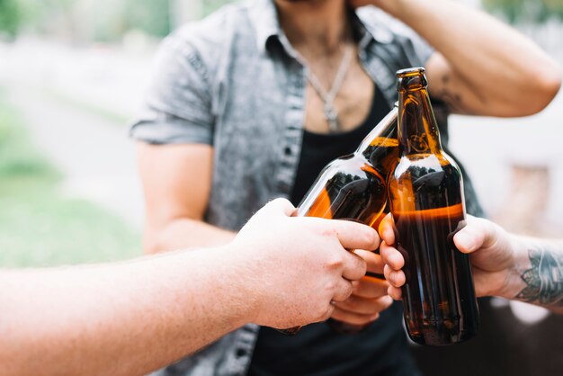 Gruppe Freunde, die draußen Bierflaschen rösten