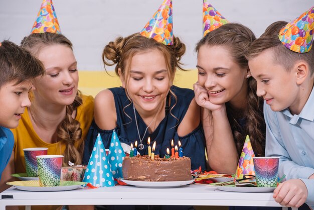 Gruppe Freunde, die Geburtstagskuchen betrachten, beleuchtete mit Kerzen