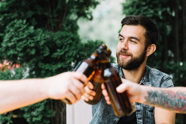 Gruppe Freunde klirren die Bierflaschen an draußen