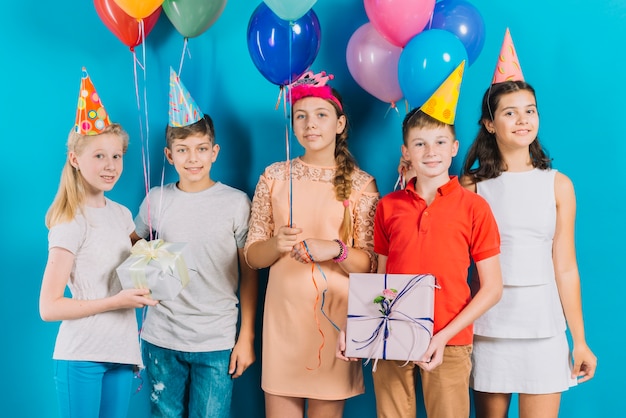 Gruppe Freunde mit Geschenken und bunten Ballonen auf blauem Hintergrund