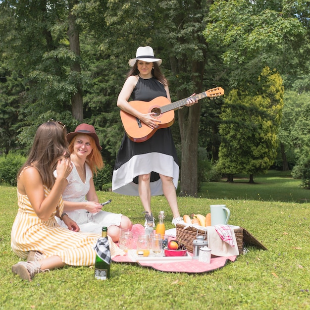 Gruppe Freundinnen, die Musik und Lebensmittel im Picknick genießen