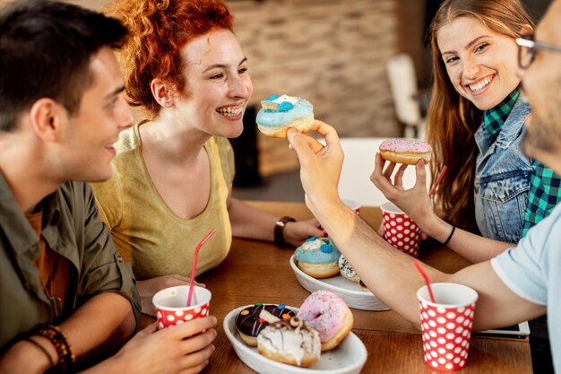 Gruppe fröhlicher Freunde, die Donuts in einem Café teilen