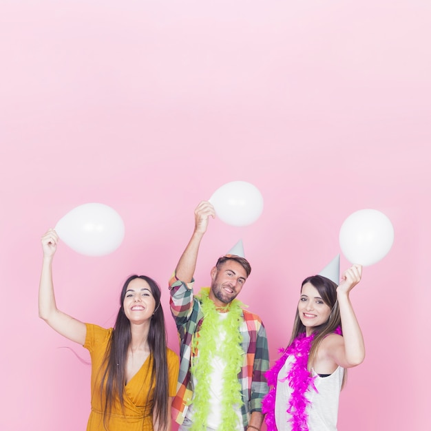 Kostenloses Foto gruppe glückliche freunde, die ballon auf rosa hintergrund halten