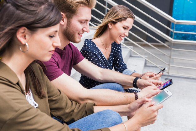 Gruppe glückliche Freunde, die Handyschirm betrachten