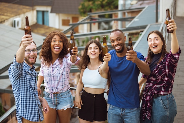 Gruppe glücklicher freunde, die am sonnigen tag bierparty haben.