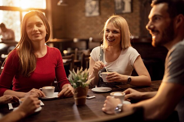 Gruppe glücklicher Freunde, die sich in einem Café treffen und ihre Kaffeezeit genießen, während sie miteinander reden