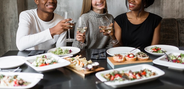 Kostenloses Foto gruppe glücklicher junger leute, die abendessen und wein haben