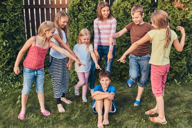 Gruppe glücklicher kleiner Freunde, die sich im Hinterhof amüsieren.