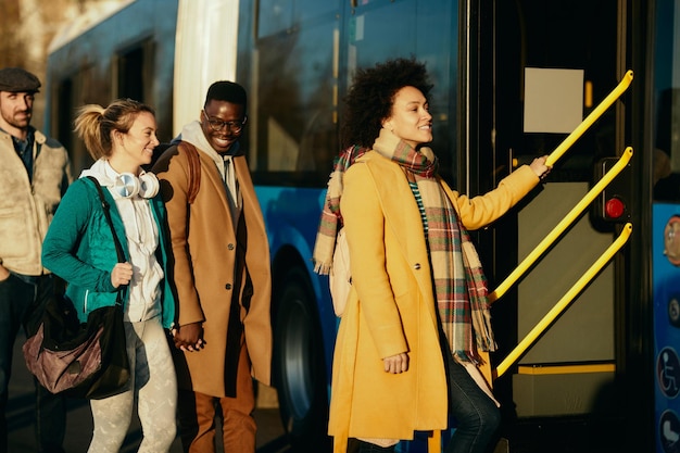 Gruppe glücklicher Menschen, die am Bahnhof in einen Bus einsteigen