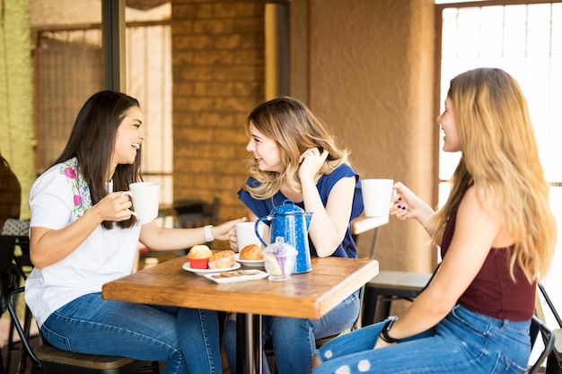 Gruppe hübscher Frauen, die zusammen in einem Restaurant Kaffee trinken und klatschen