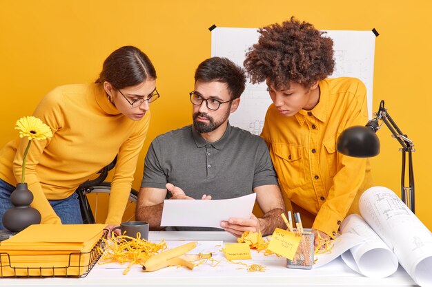 Gruppe internationaler Architekten diskutieren Ideen für Engineering-Projekte genießen den gemeinsamen Arbeitsprozess am Desktop konzentriert an der gelben Papierwand. Diverse Kollegen Gasthausbüro.