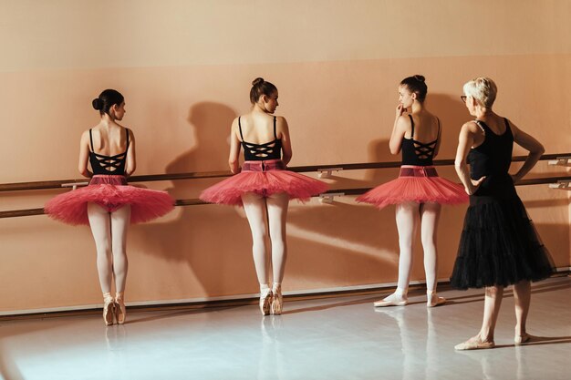 Gruppe jugendlicher Ballerinas, die en pointe üben, während sie eine Klasse mit Ballettlehrer im Tanzstudio haben