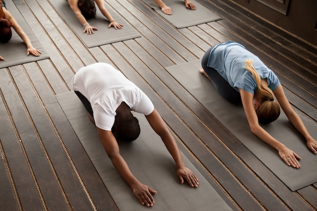 Gruppe junge Leute in Balasana-Haltung, Draufsicht